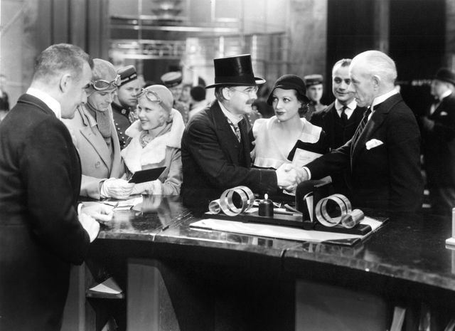 映画『グランド・ホテル』より　中央のシルクハットの帽子をかぶった男性がクリンゲライン（ライオネル・バリモア）、その右隣がフレムヘン（ジョーン・クロフォード）