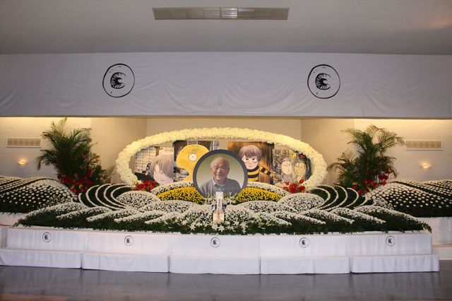 祭壇は白菊を中心とした2,000本以上の花々で埋め尽くされ、キャラクターのパネルが飾れられた