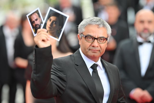 イランを出られなかった俳優たちの写真を手にしたモハマド・ラスロフ監督 - 第77回カンヌ国際映画祭にて